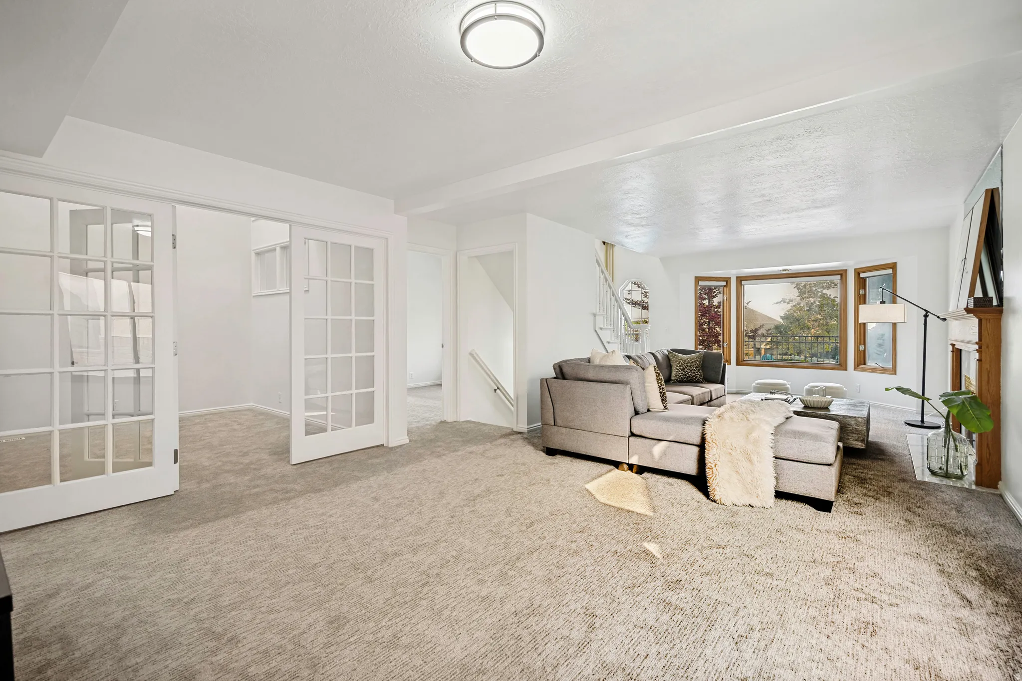 Living area featuring light-toned carpet flooring, a bay window with wood trim, and a built-in wood fireplace surround