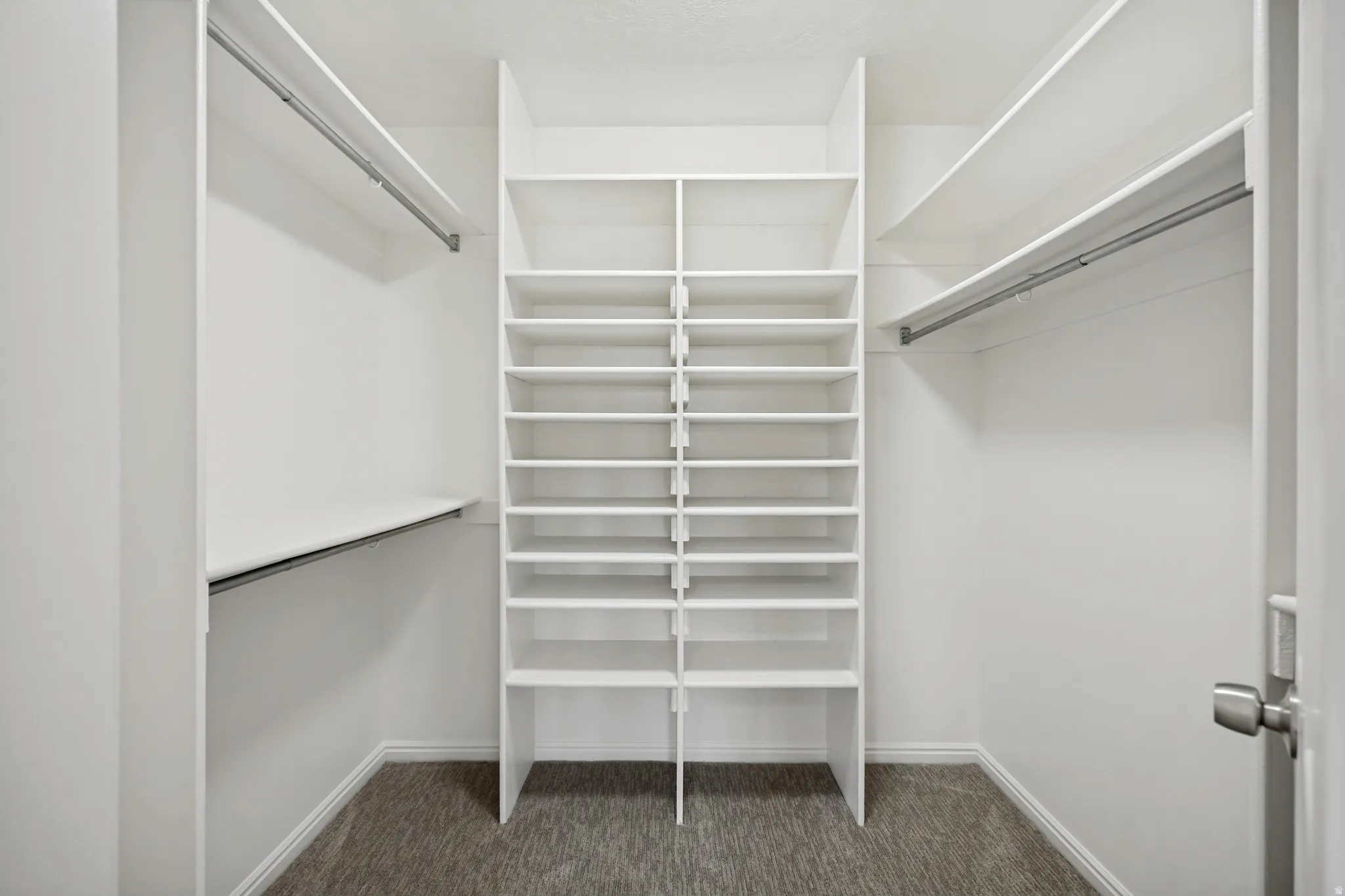 Walk-in closet featuring built-in shelving, multiple hanging rods, and neutral carpet flooring