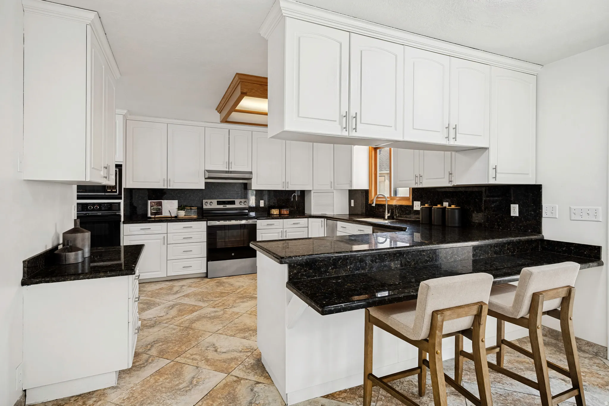 Kitchen featuring white cabinetry, dark stone countertops, stainless steel appliances, a built-in oven, and tile flooring