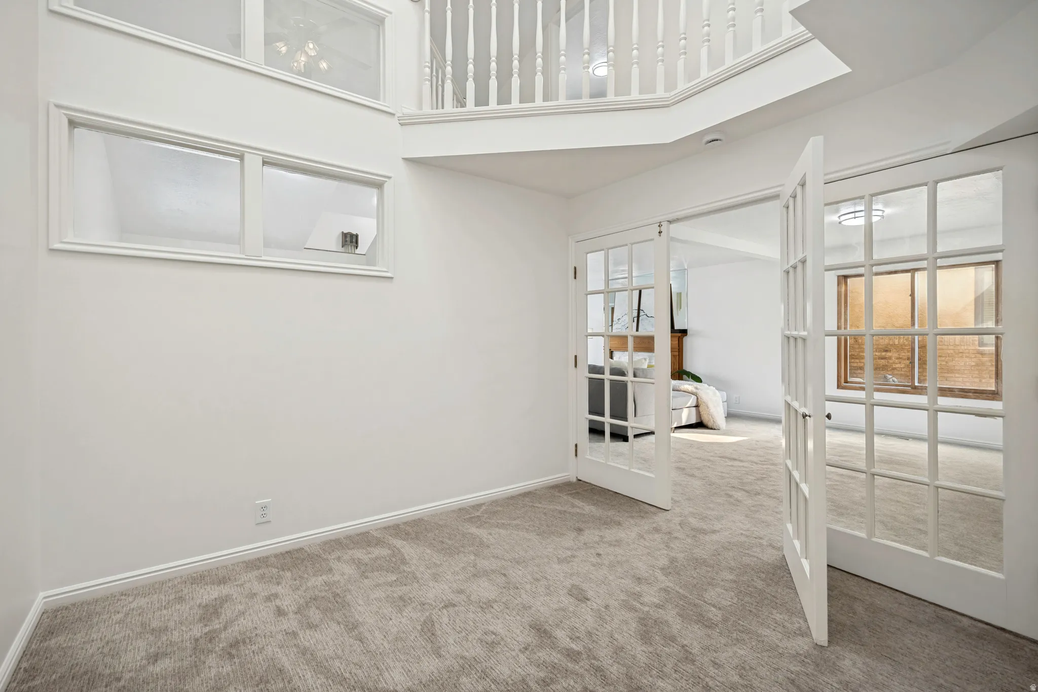 Two-story entry foyer featuring a balcony overlook, white spindle railing, and multiple transom windows