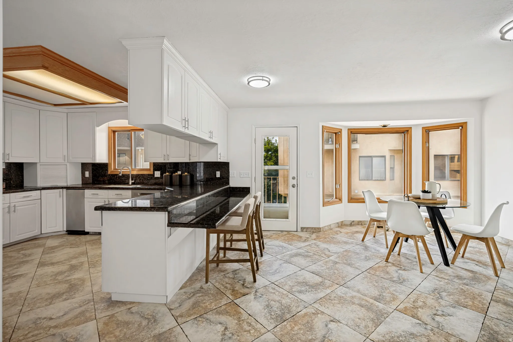 Kitchen featuring white cabinetry, dark stone countertops, and a peninsula with bar seating