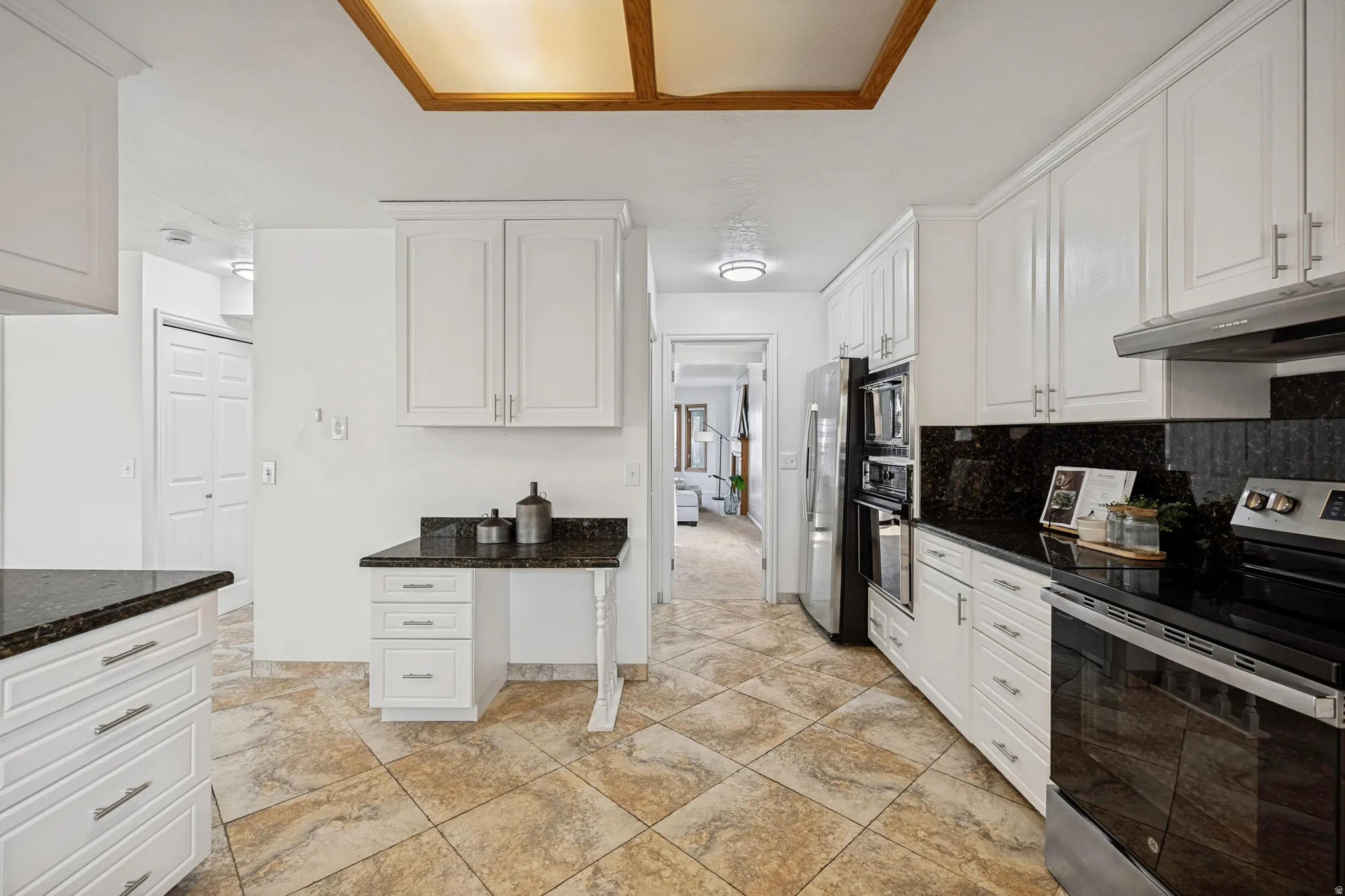 Kitchen featuring white cabinetry, dark stone countertops, stainless steel appliances, tile flooring, and recessed lighting