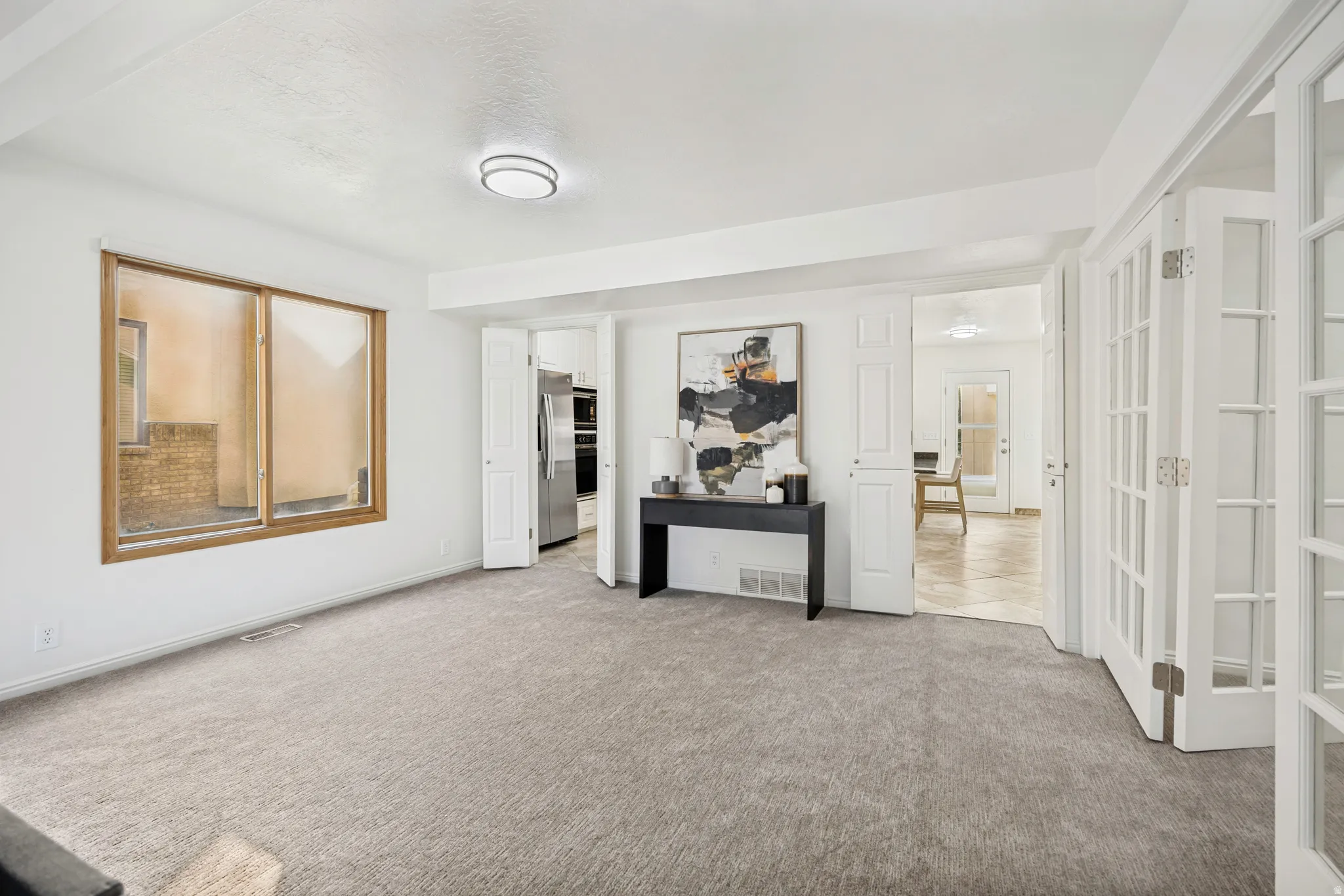 Carpeted interior space featuring a large wooden-framed window and recessed lighting