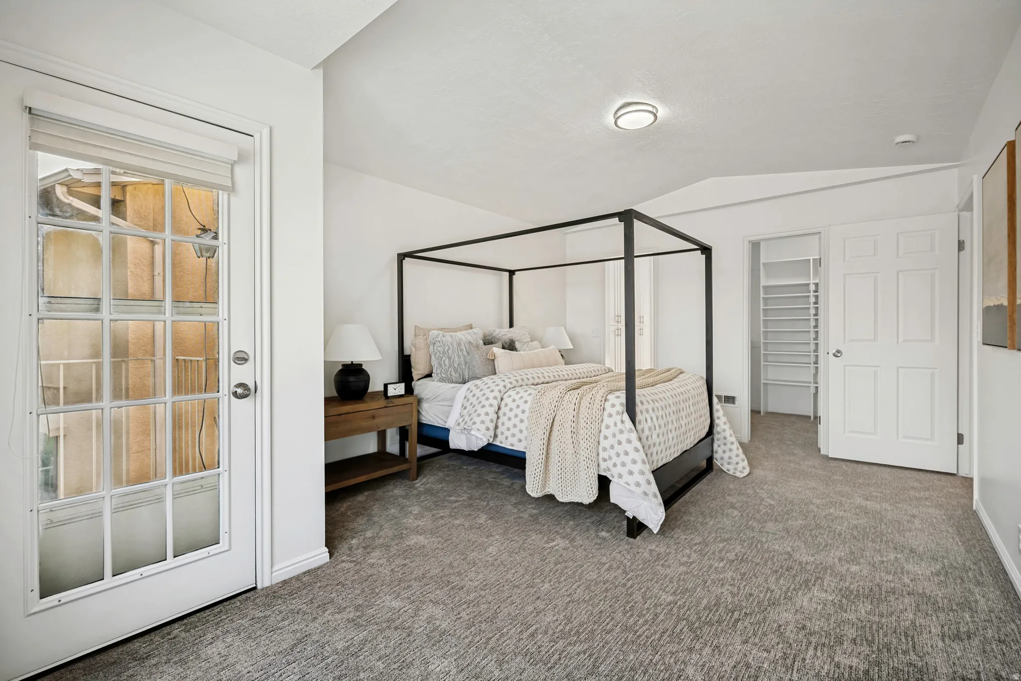 Room featuring vaulted ceilings, plush carpeting, and a french door with frosted glass panes