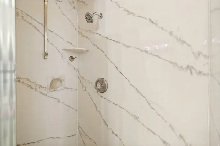 Shower enclosure featuring white and grey veined wall panels