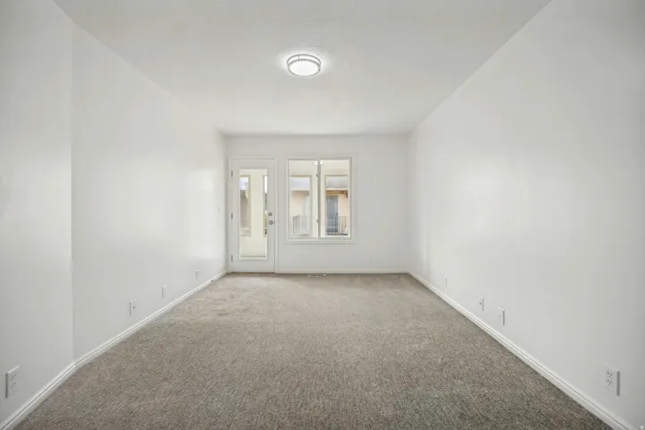 Neutral carpeted room featuring white walls and a ceiling-mounted light fixture