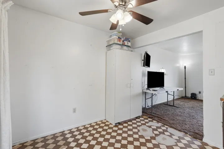 Room with patterned flooring, an overhead ceiling fan, and a built-in storage cabinet