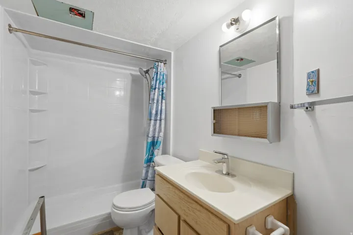 Full bathroom featuring a white shower-over-tub unit, a toilet, and a vanity with an integrated sink