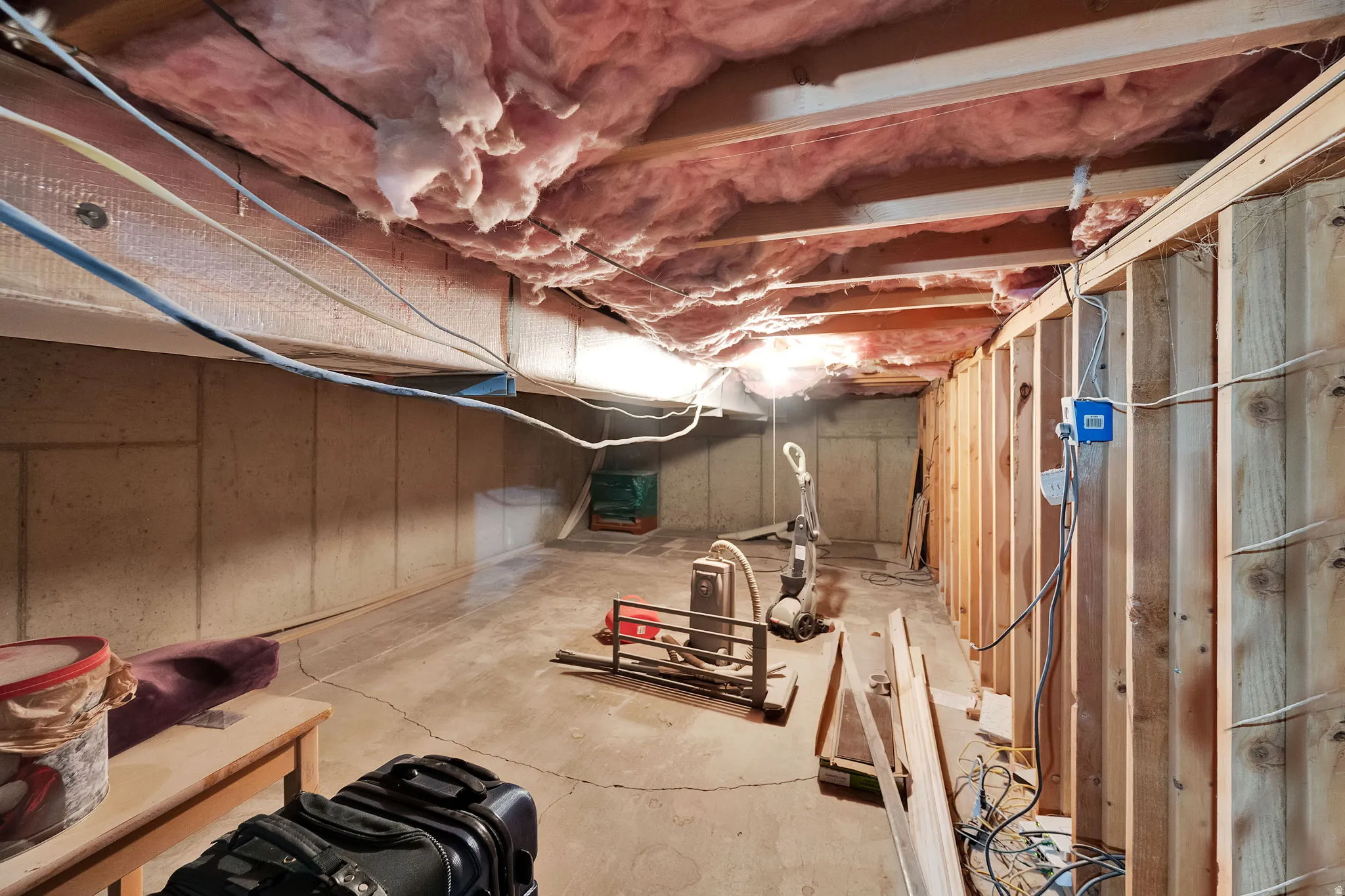 Unfinished basement space featuring exposed wood framing, concrete foundation walls, and a concrete floor