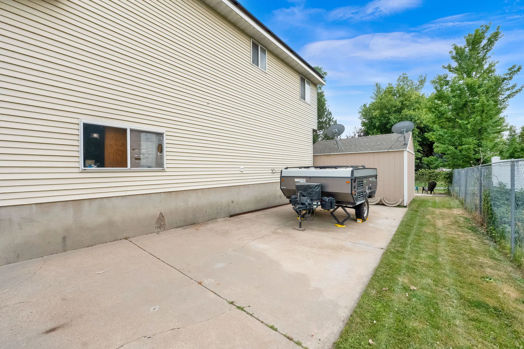 Exterior siding with a window, concrete patio, and a storage shed