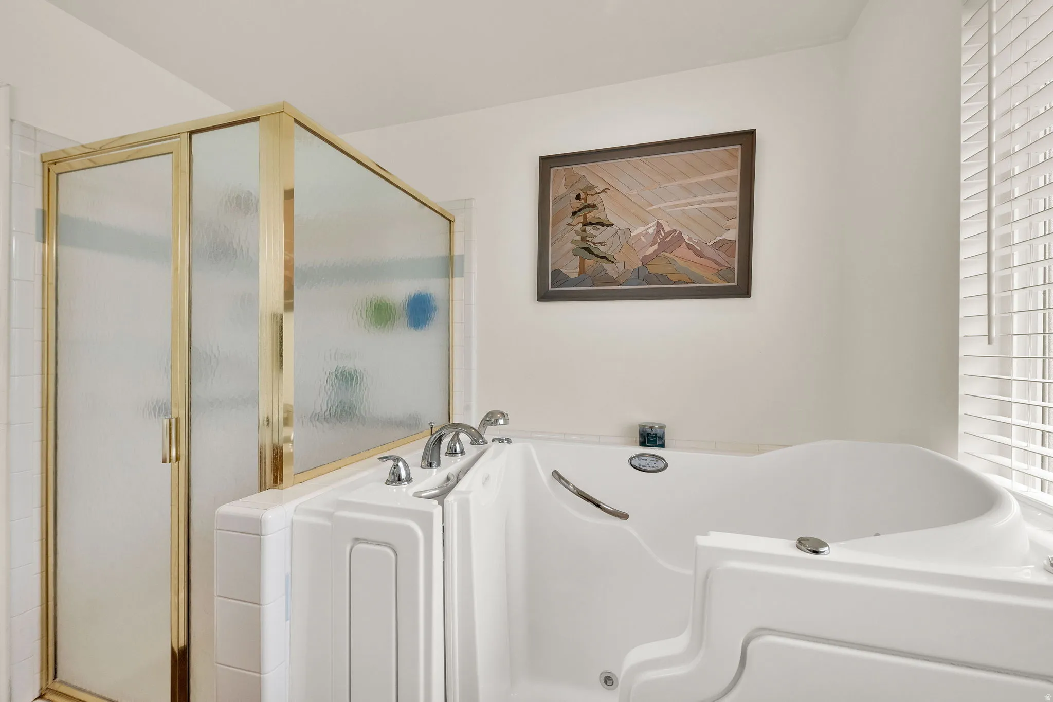 Walk-in tub with chrome fixtures, brass-framed shower enclosure, and white horizontal blinds