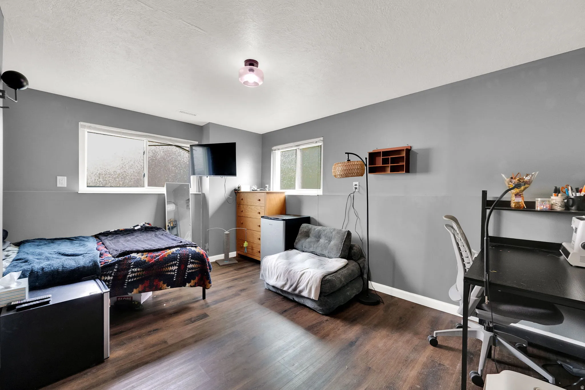 Interior space featuring wood-finish flooring, two large windows, a built-in wall shelf, and neutral gray walls