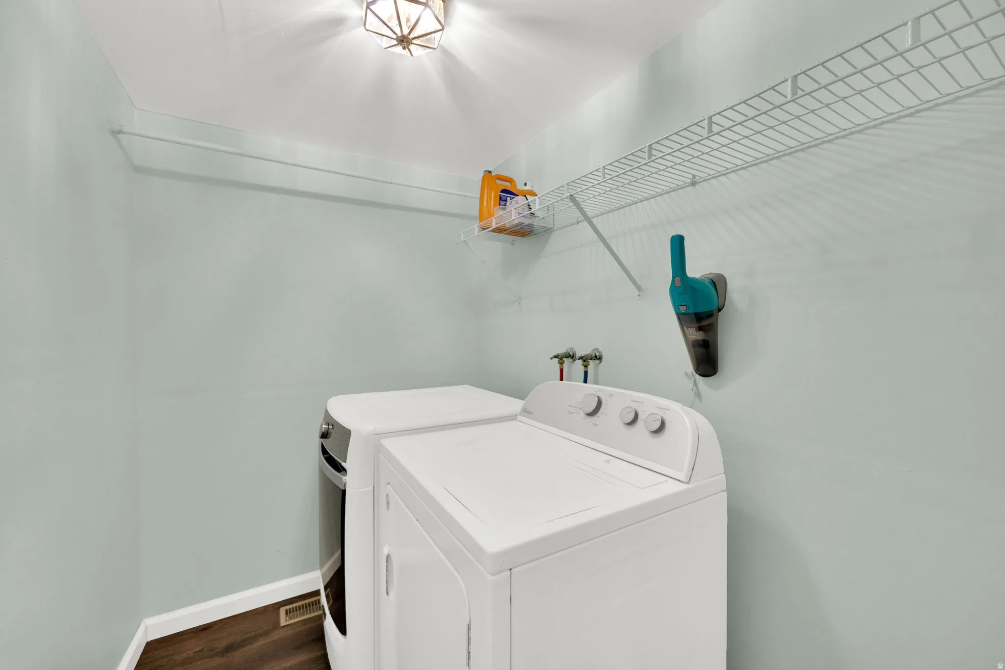 Dedicated laundry area featuring a light blue wall color and wood-finish flooring