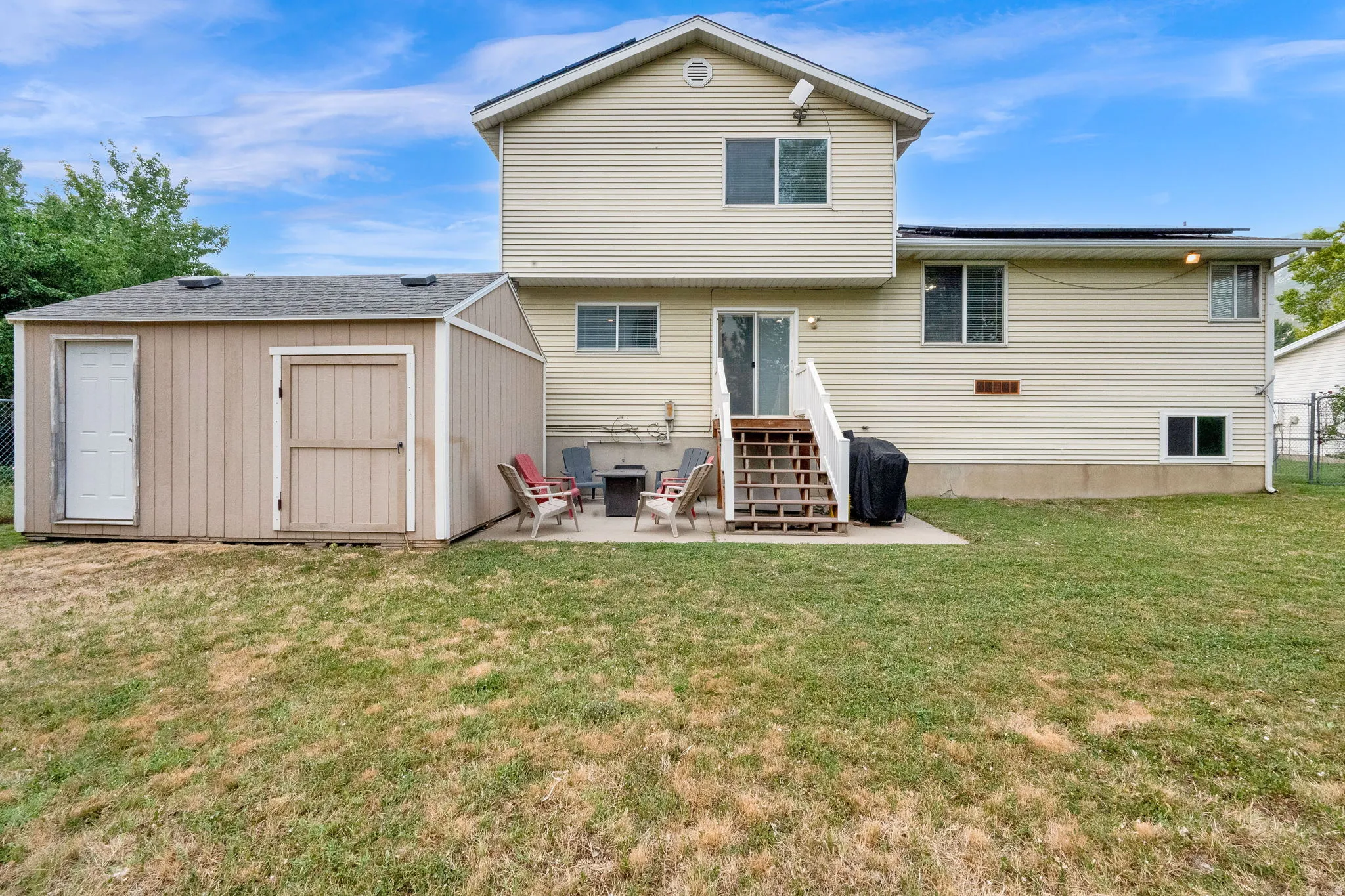 Rear exterior with horizontal siding, an outdoor patio, and a separate storage shed