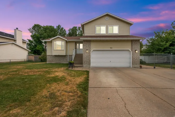 Split-level residence featuring a two-car garage, concrete driveway, and a front bay window
