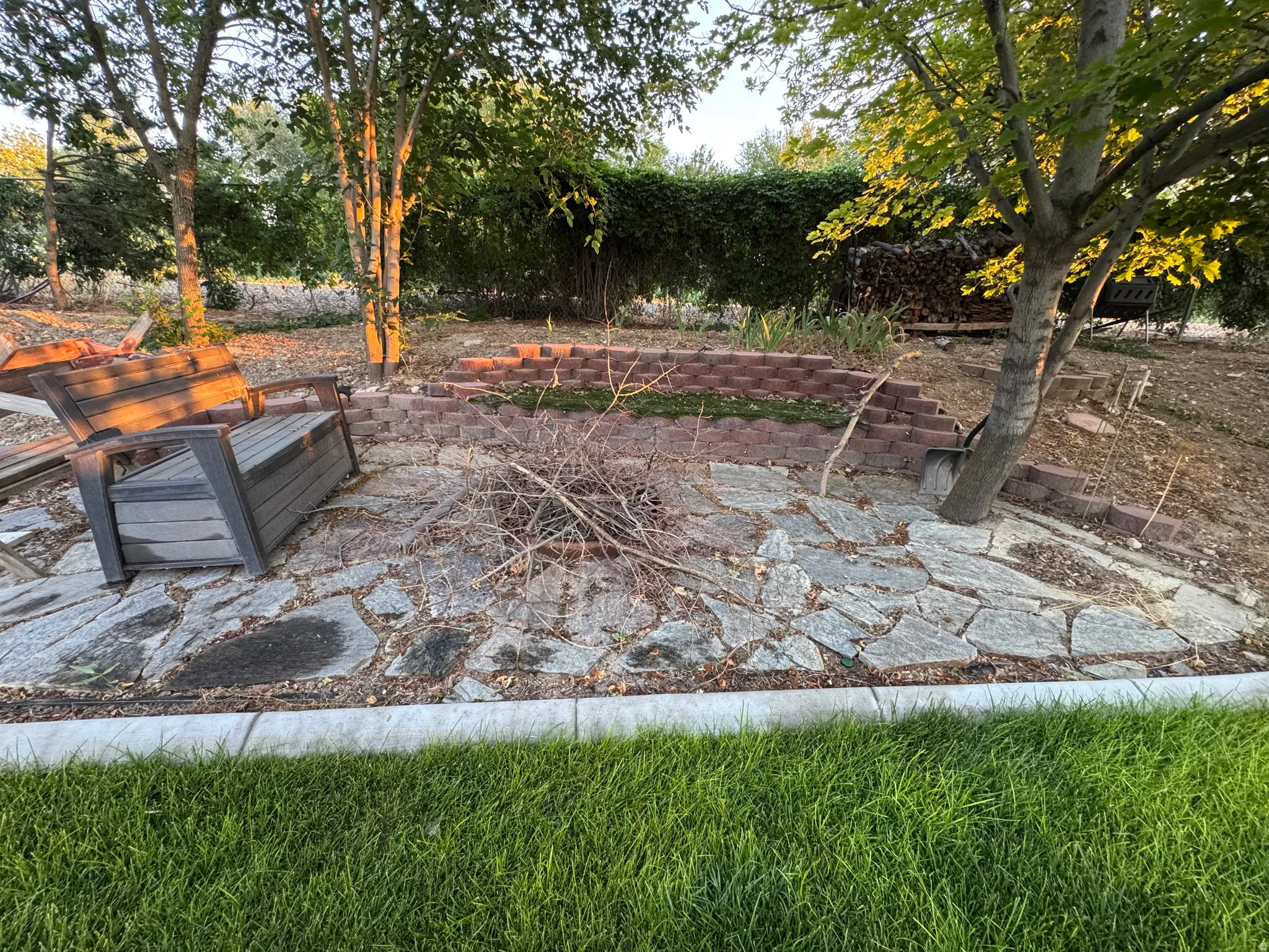 Outdoor Firepit space featuring a flagstone patio, brick retaining walls, and mature trees