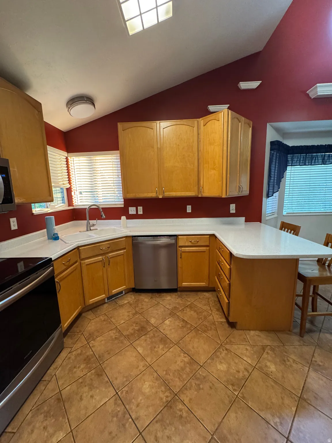 Kitchen featuring wood cabinetry, white countertops, stainless steel appliances, and diagonal tile flooring