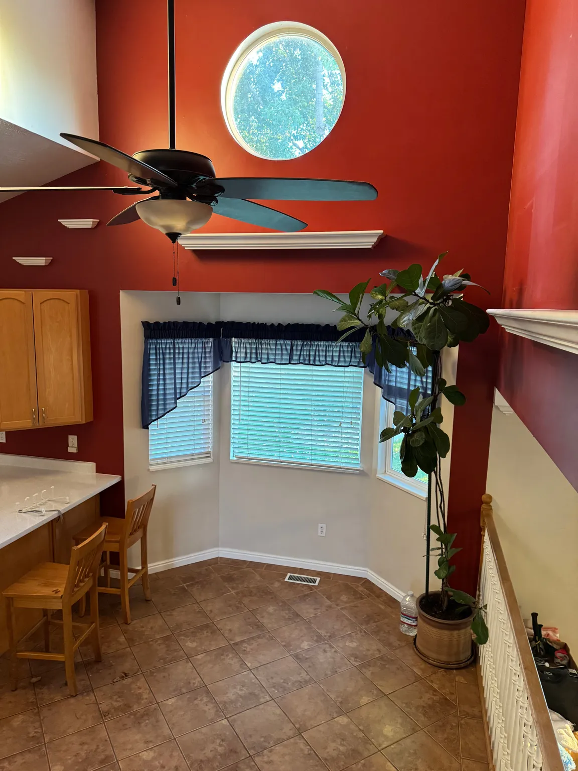 Two-story ceiling with a circular architectural window and contemporary ceiling fan