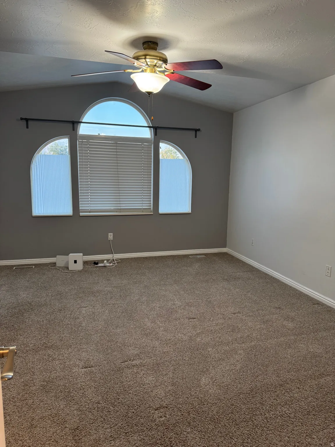 Room featuring a vaulted ceiling with a brass-toned ceiling fan and light fixture