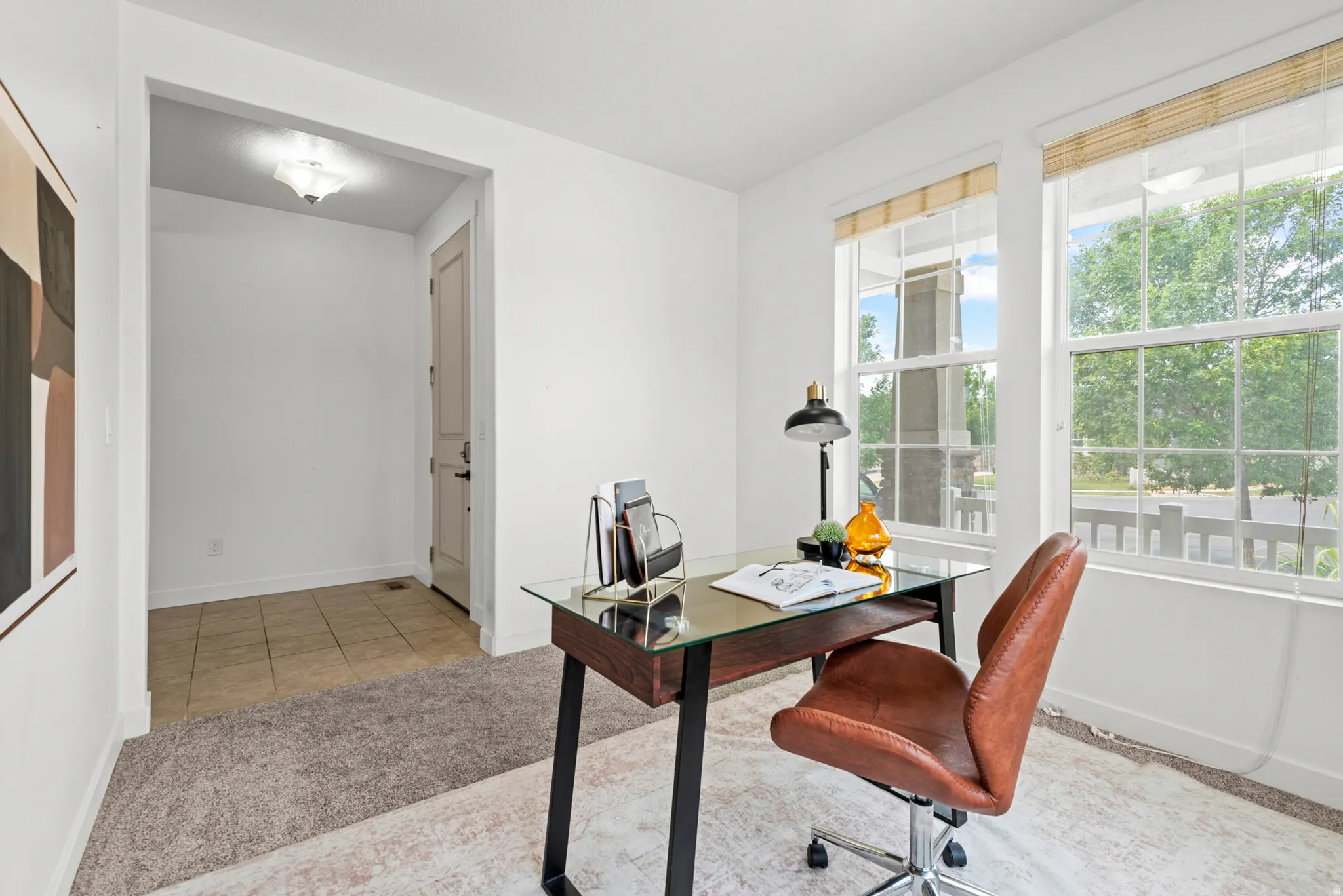 Light-filled room featuring two large windows with natural wood blinds, plush carpeting, and a tiled entryway