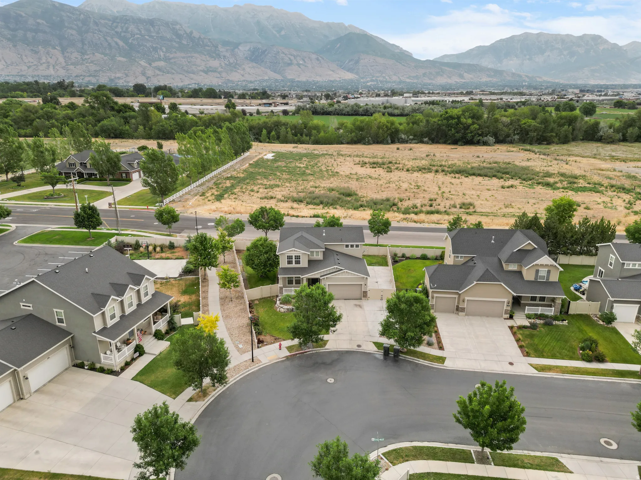 Aerial perspective showcasing a residential street with cul-de-sac, multiple homes, and expansive natural landscape
