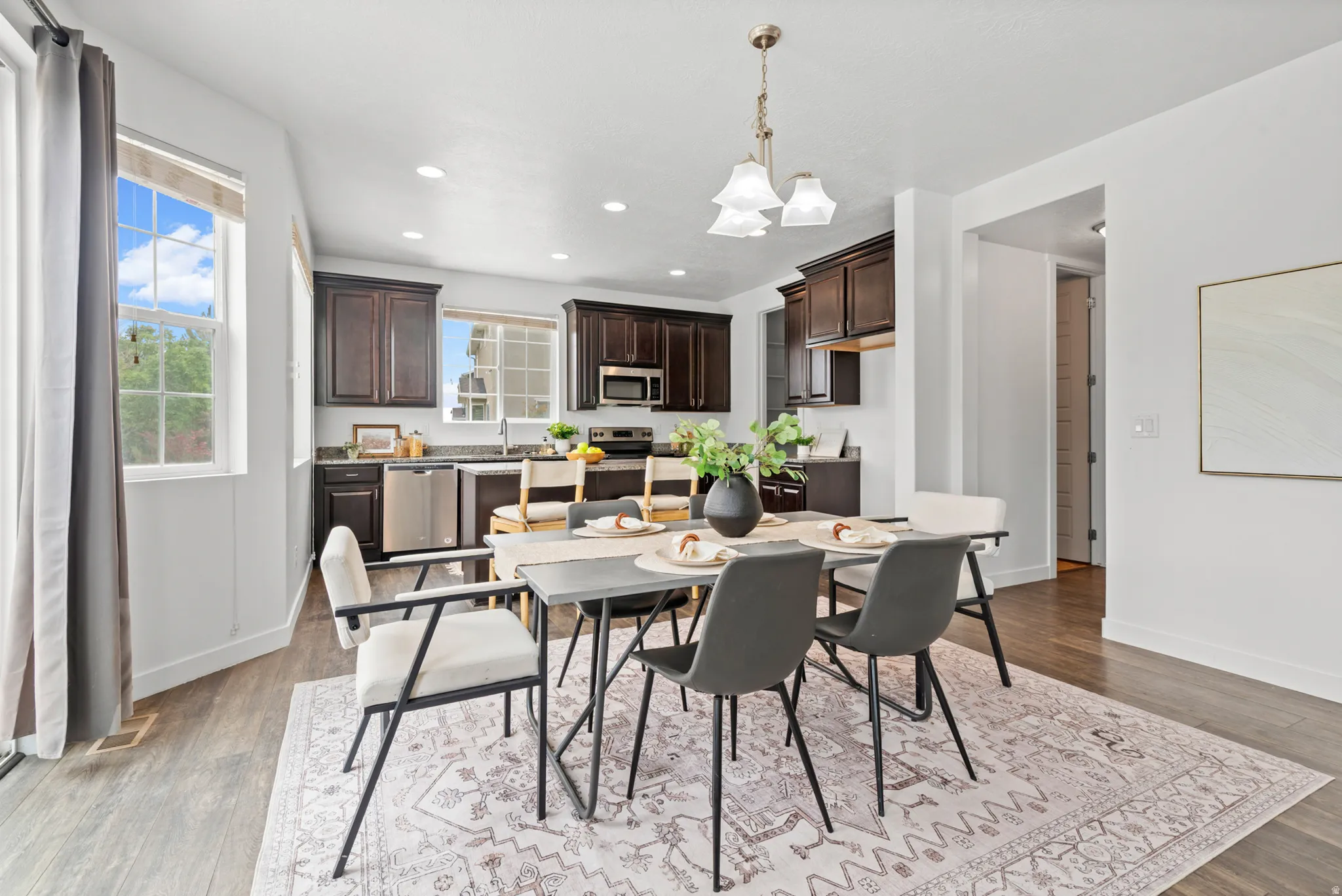 Open concept dining area featuring a contemporary chandelier and wood-finish flooring