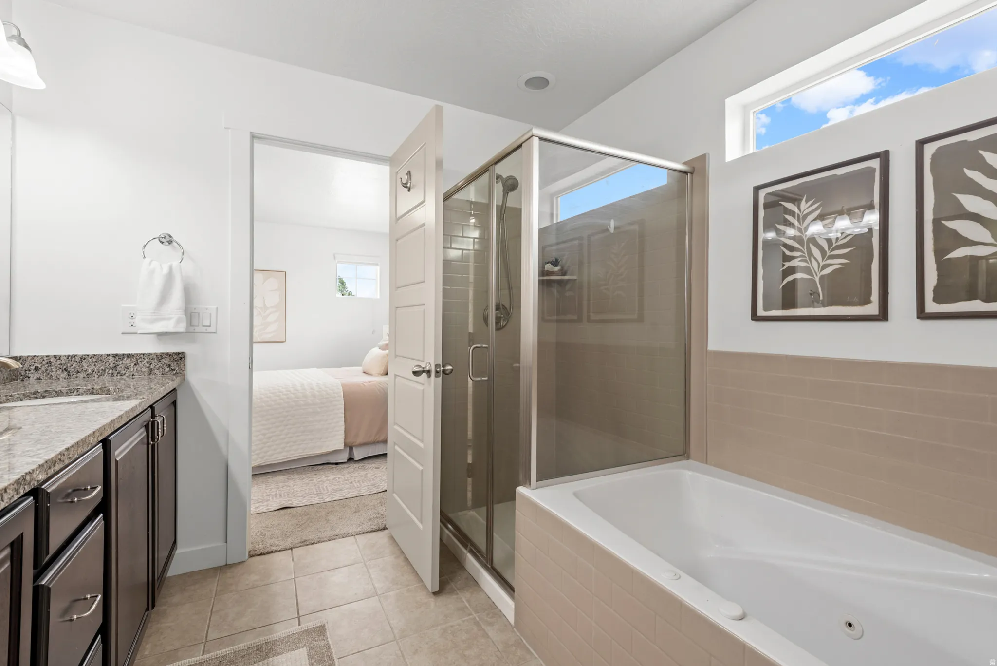 Bathroom featuring a built-in tub, separate glass-enclosed shower, single vanity with a stone countertop, and tile flooring