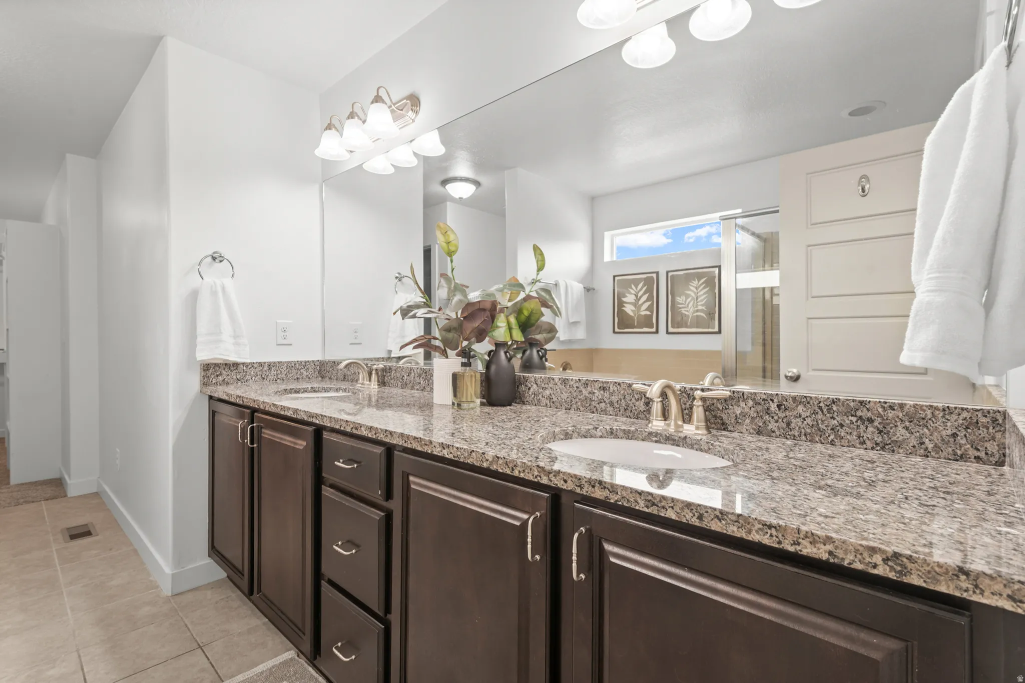 Dual vanity featuring a granite countertop, undermount sinks, and dark wood cabinetry