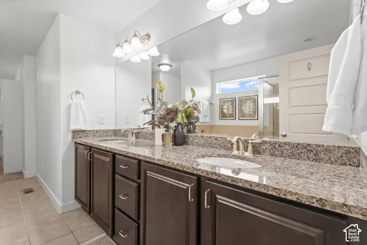 Dual vanity featuring a granite countertop, undermount sinks, and dark wood cabinetry