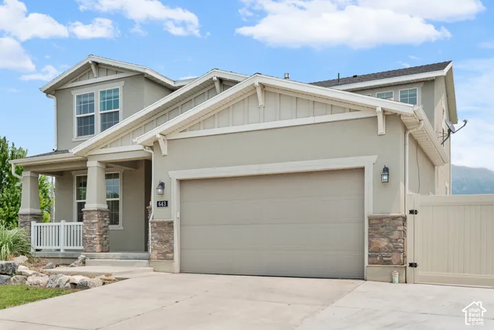 Contemporary two-story residence featuring a two-car garage, stone veneer accents, and a covered porch with white railing