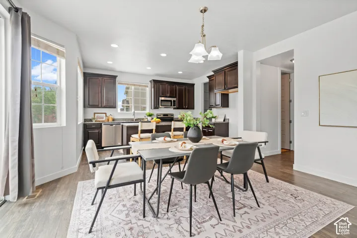 Open concept dining area featuring a contemporary chandelier and wood-finish flooring