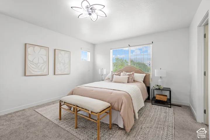 Carpeted room featuring a large window with blinds, a smaller upper window, and a modern ceiling light fixture