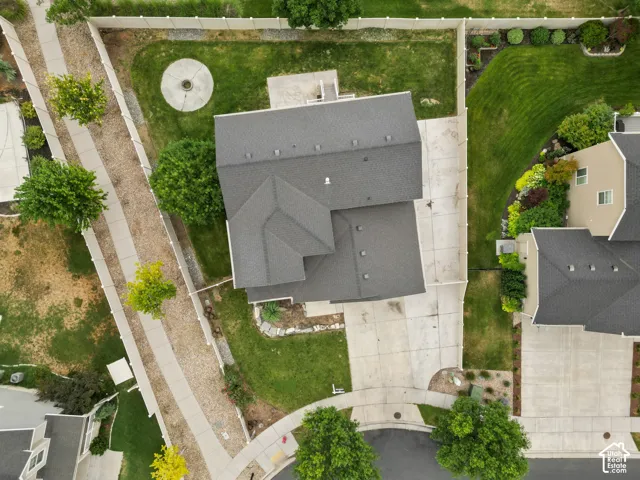 Property featuring a dark shingle roof, concrete driveway, and established landscaping