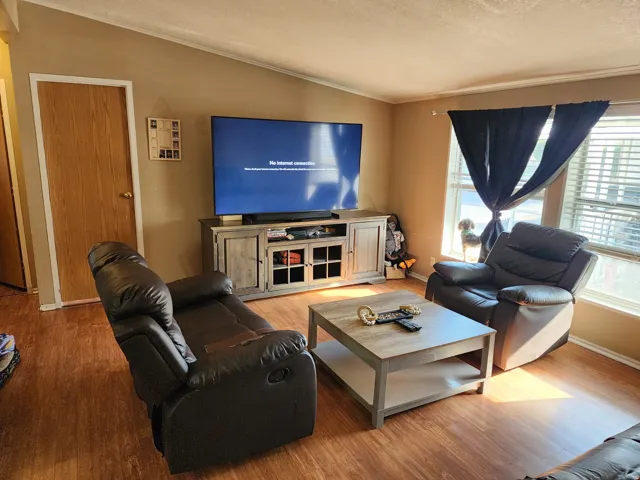 Living area featuring wood-finish flooring, warm-toned wall paint, and a white ceiling with crown molding