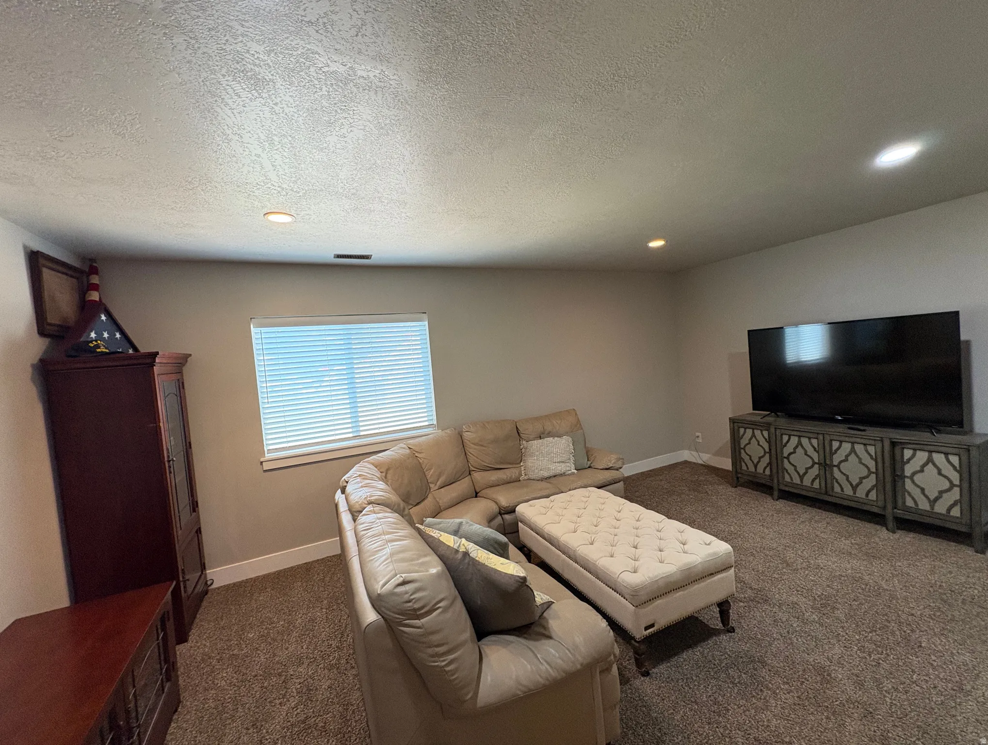 Carpeted room with recessed lighting and a single window featuring horizontal blinds