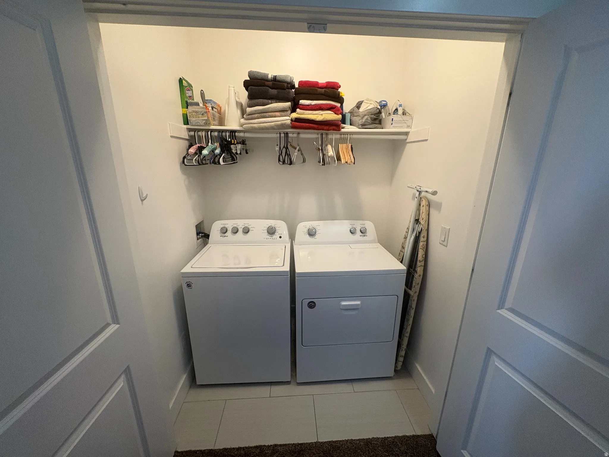 Dedicated laundry closet featuring a top-load washer, front-load dryer, and a built-in wall shelf for storage