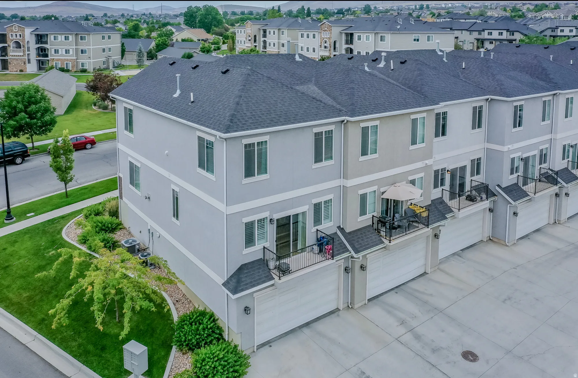 Townhome exterior featuring light gray siding with white trim, a dark gray shingle roof, and a private balcony with black railings