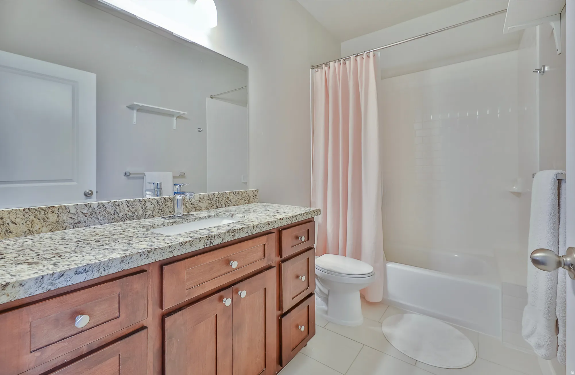 Bathroom with a single vanity featuring a granite-look countertop and wood-finish cabinetry