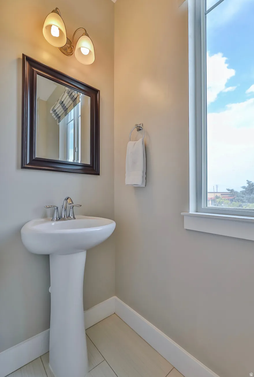 Pedestal sink with chrome faucet, framed mirror, and two-light vanity fixture