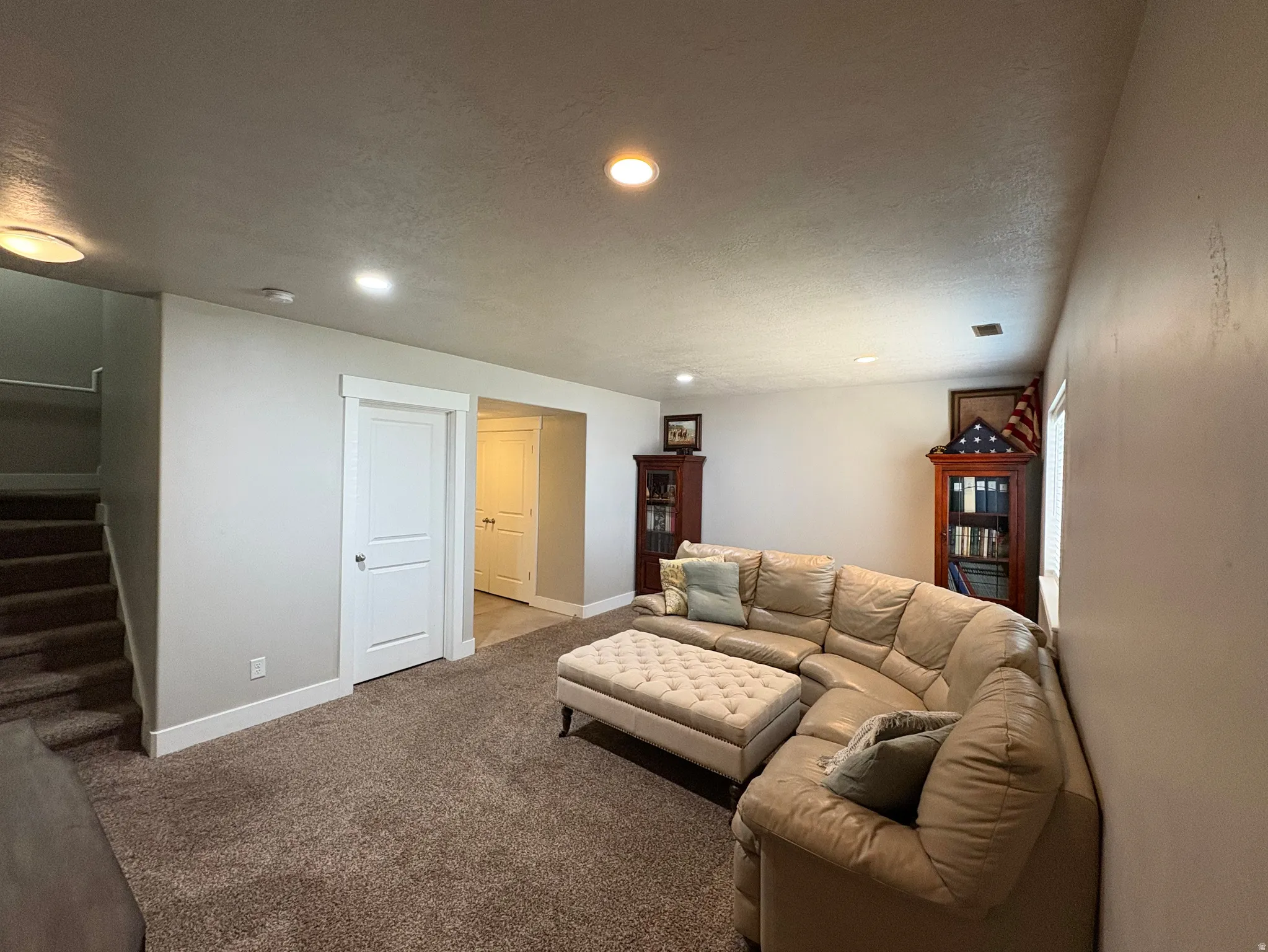 Spacious room featuring neutral carpeting, recessed ceiling lighting, a white two-panel door with white trim, and light-toned wall paint