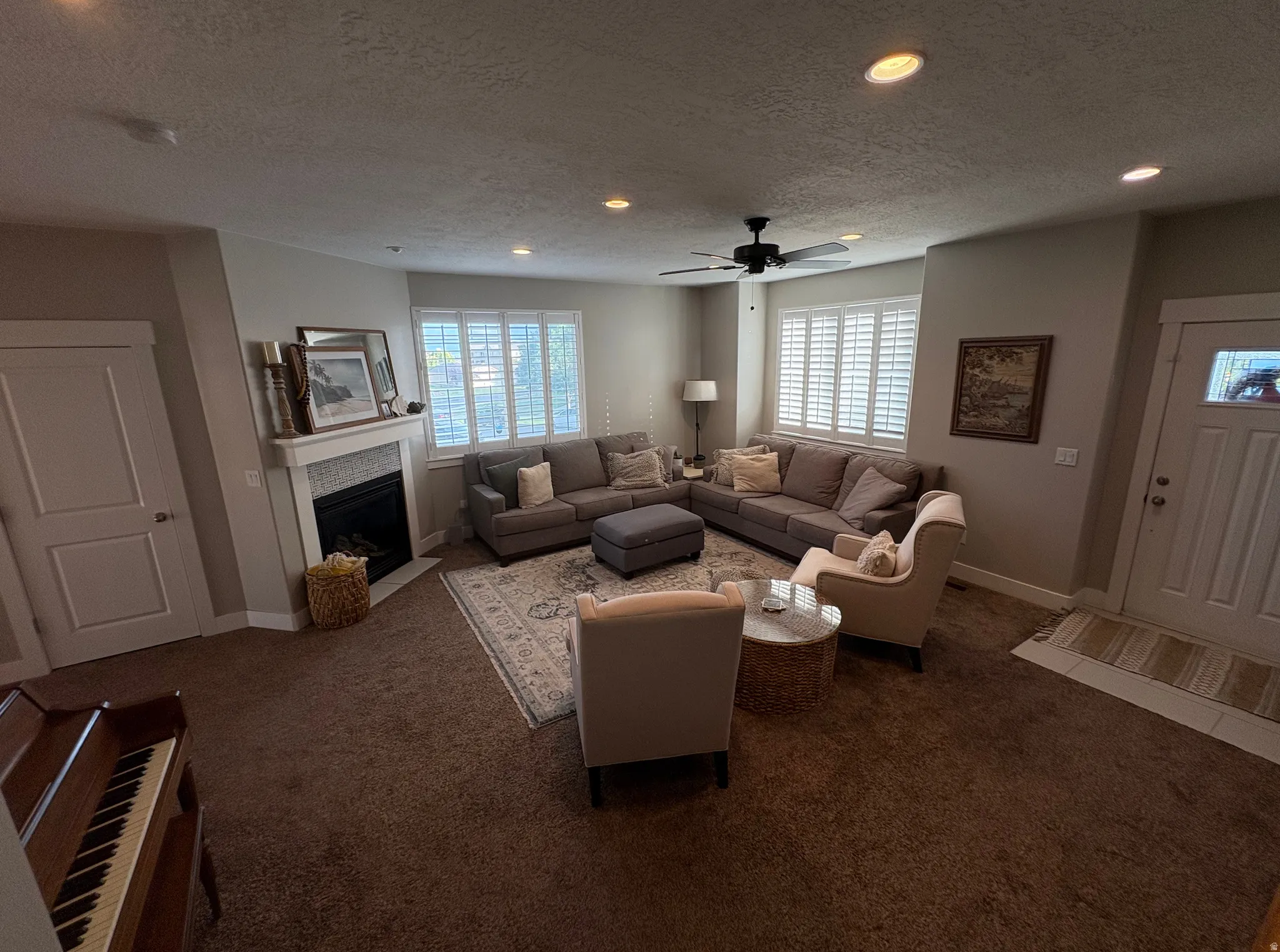 Spacious living area featuring a fireplace with a tiled surround, recessed lighting, and a ceiling fan