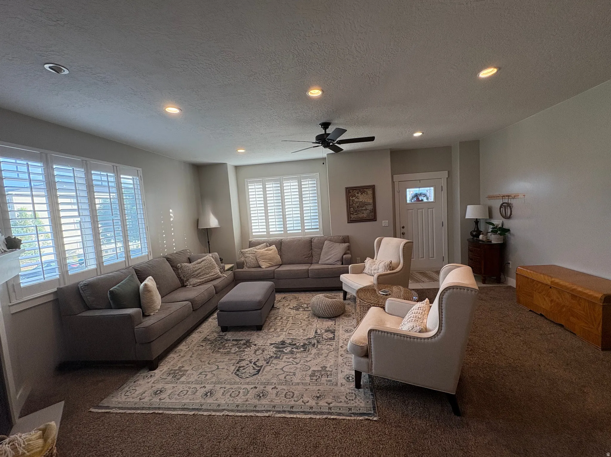 Spacious living area featuring recessed lighting, a ceiling fan, and multiple windows with white plantation shutters