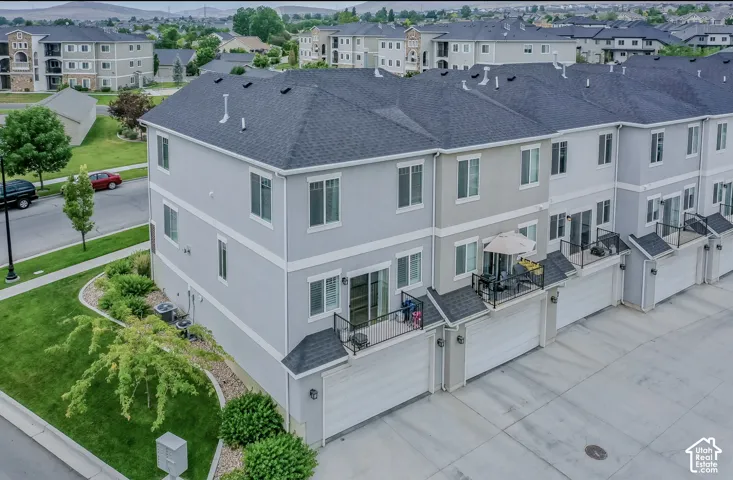 Townhome exterior featuring light gray siding with white trim, a dark gray shingle roof, and a private balcony with black railings