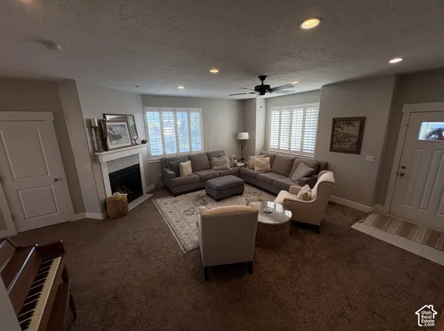 Spacious living area featuring a fireplace with a tiled surround, recessed lighting, and a ceiling fan