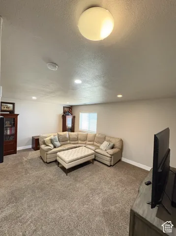 Carpeted room featuring a ceiling-mounted light fixture, recessed lighting, and a white-framed window with horizontal blinds