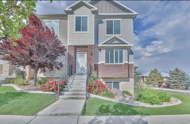 Multi-level townhome exterior featuring an inviting entryway with concrete steps and metal railings