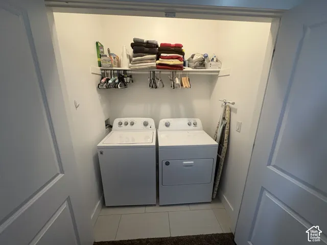 Dedicated laundry closet featuring a top-load washer, front-load dryer, and a built-in wall shelf for storage