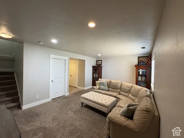 Spacious room featuring neutral carpeting, recessed ceiling lighting, a white two-panel door with white trim, and light-toned wall paint