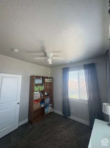 Carpeted room featuring a ceiling fan, a window with blinds and drapes, and a white interior door