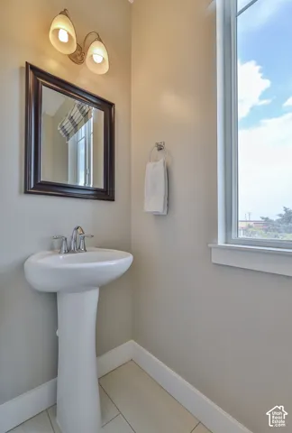 Pedestal sink with chrome faucet, framed mirror, and two-light vanity fixture